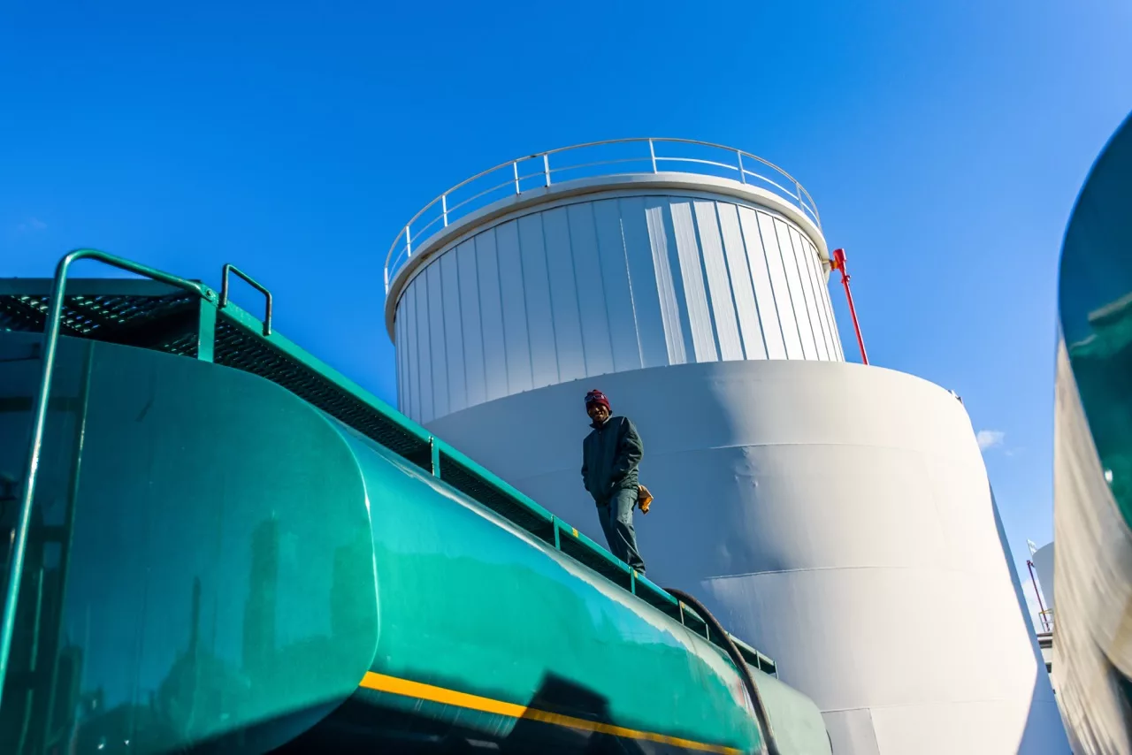 Low angle view of worker on top of biofuel oil tanker at biofuel plant