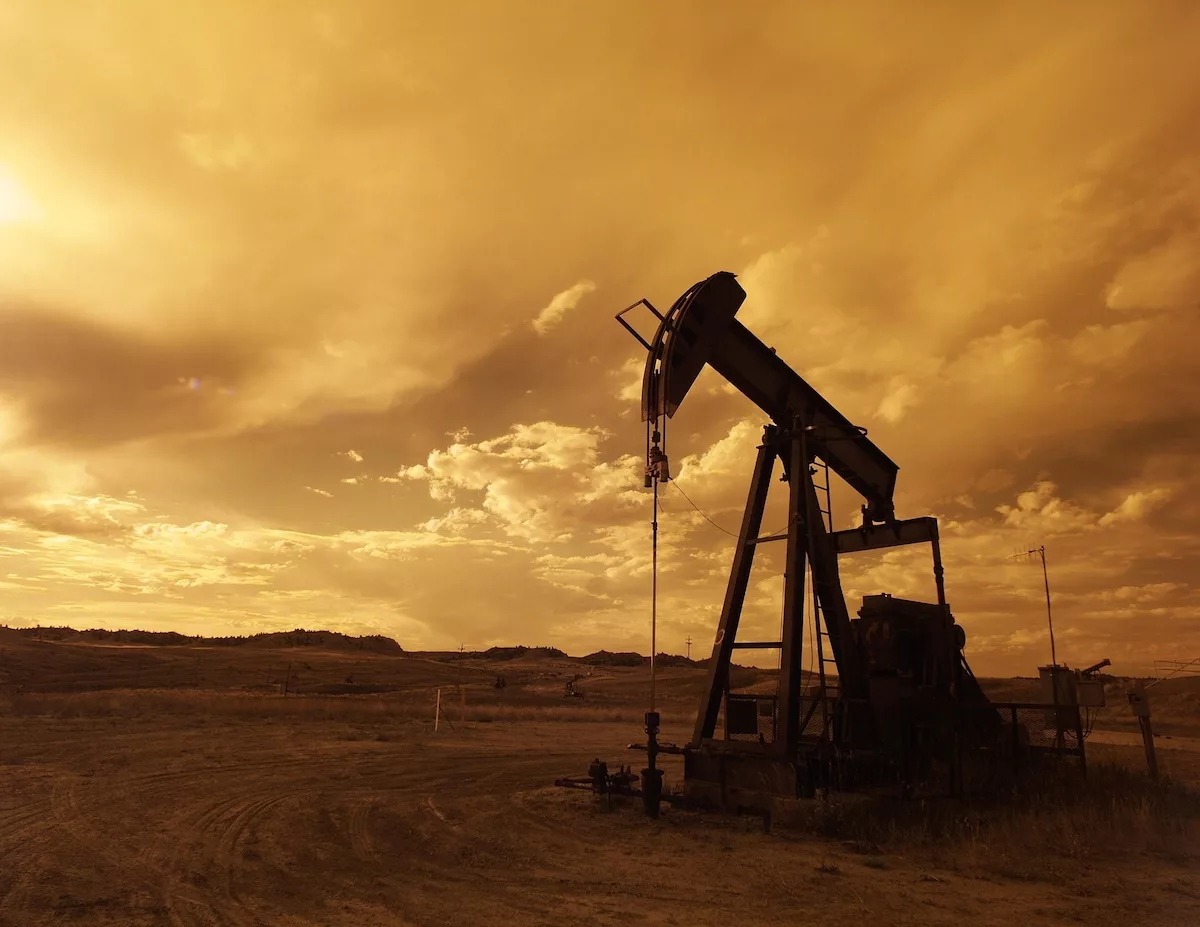 An oil pump against a sunset and cloudy sky showing subsurface energy