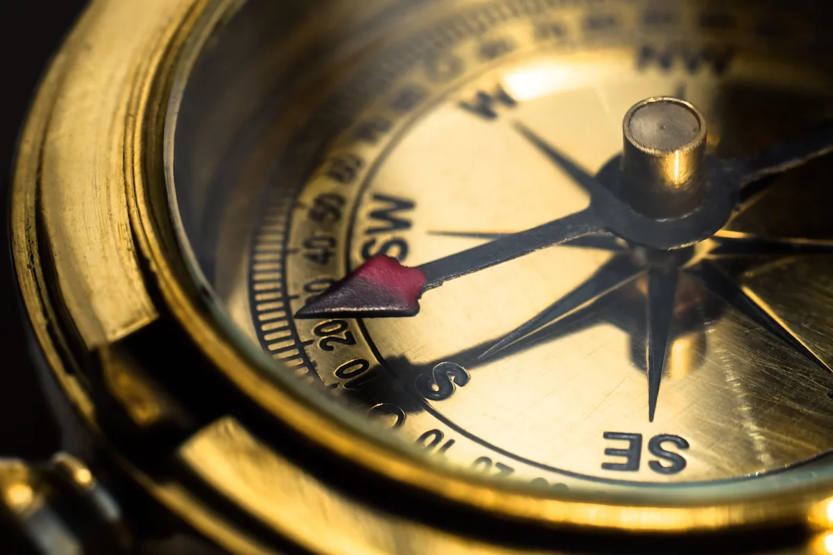 Closeup on a gloden brass compass pointing to south direction