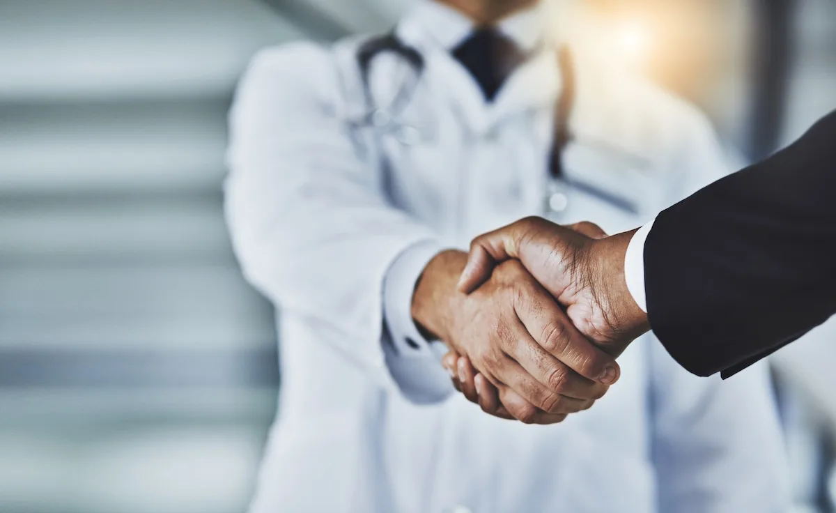 Cropped shot of a doctor shaking hands with a businessman in a hospital.